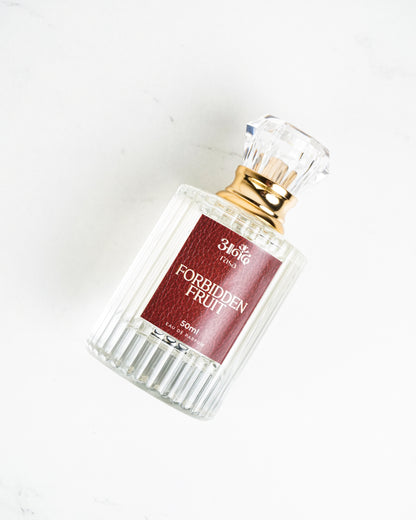 50ml Forbidden Fruit perfume by Sakura with clear ribbed glass bottle and gold cap on white marble background - handcrafted attar - Anandrasa