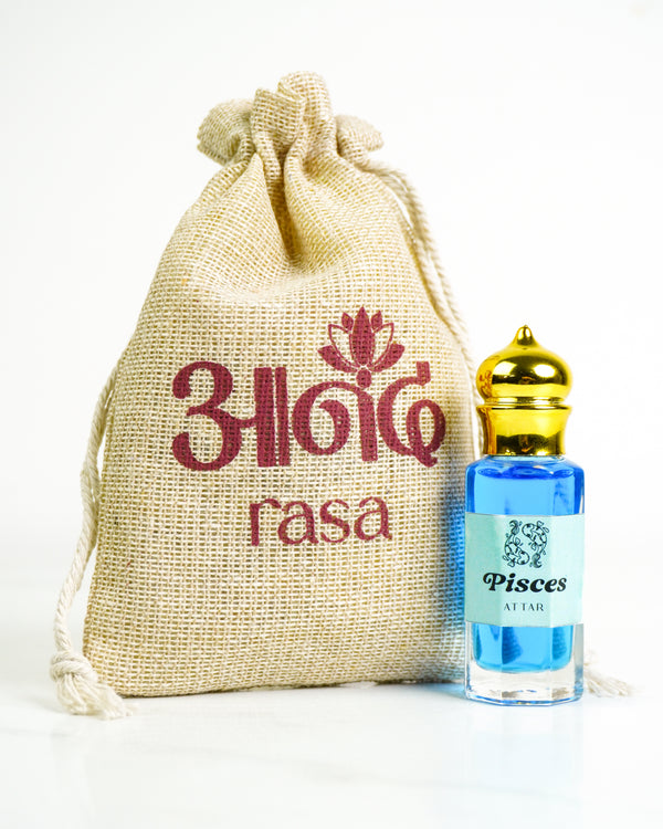 Rasa Pisces Attar perfume in a blue glass bottle with gold cap beside a branded burlap pouch on a white background