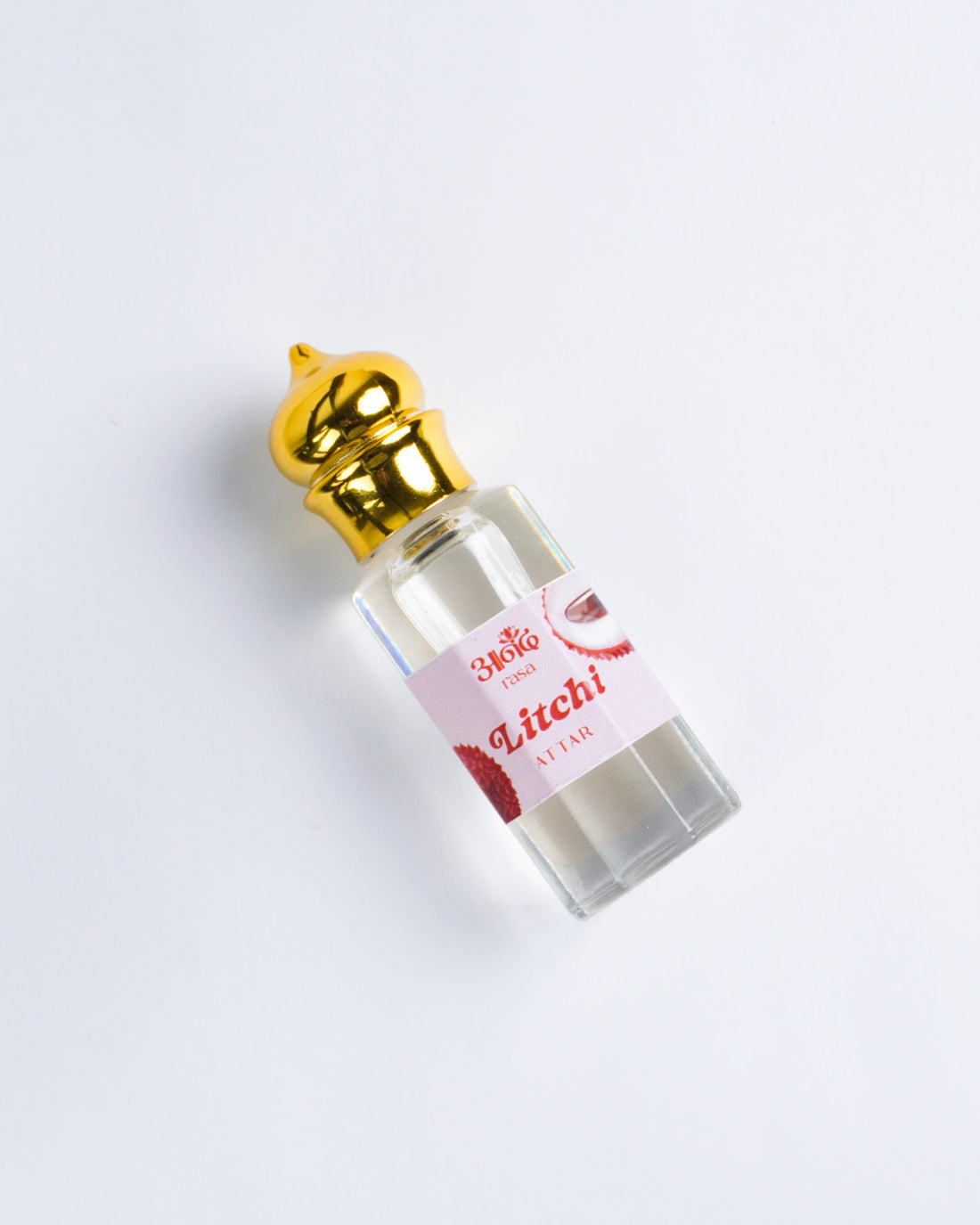 Lychee Attar perfume bottle surrounded by fresh red lychees and peeled lychee fruit on a soft pink background