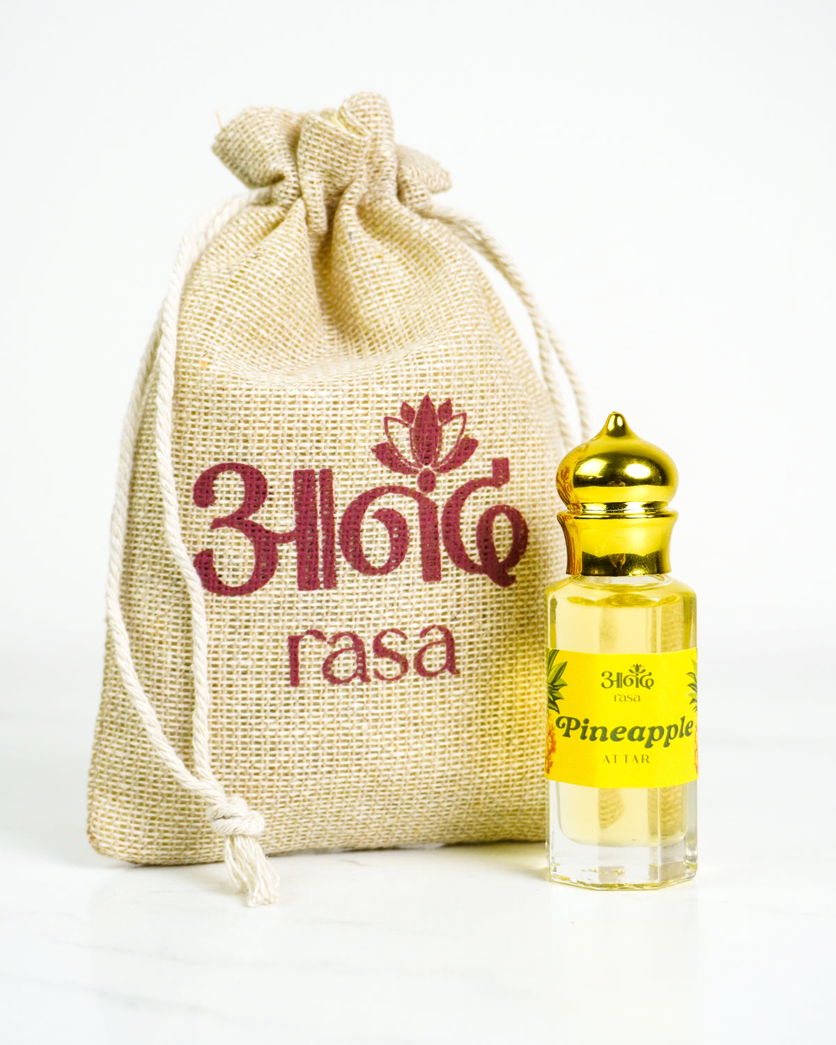 Pineapple scented attar perfume with fresh pineapple fruit on a vibrant red background