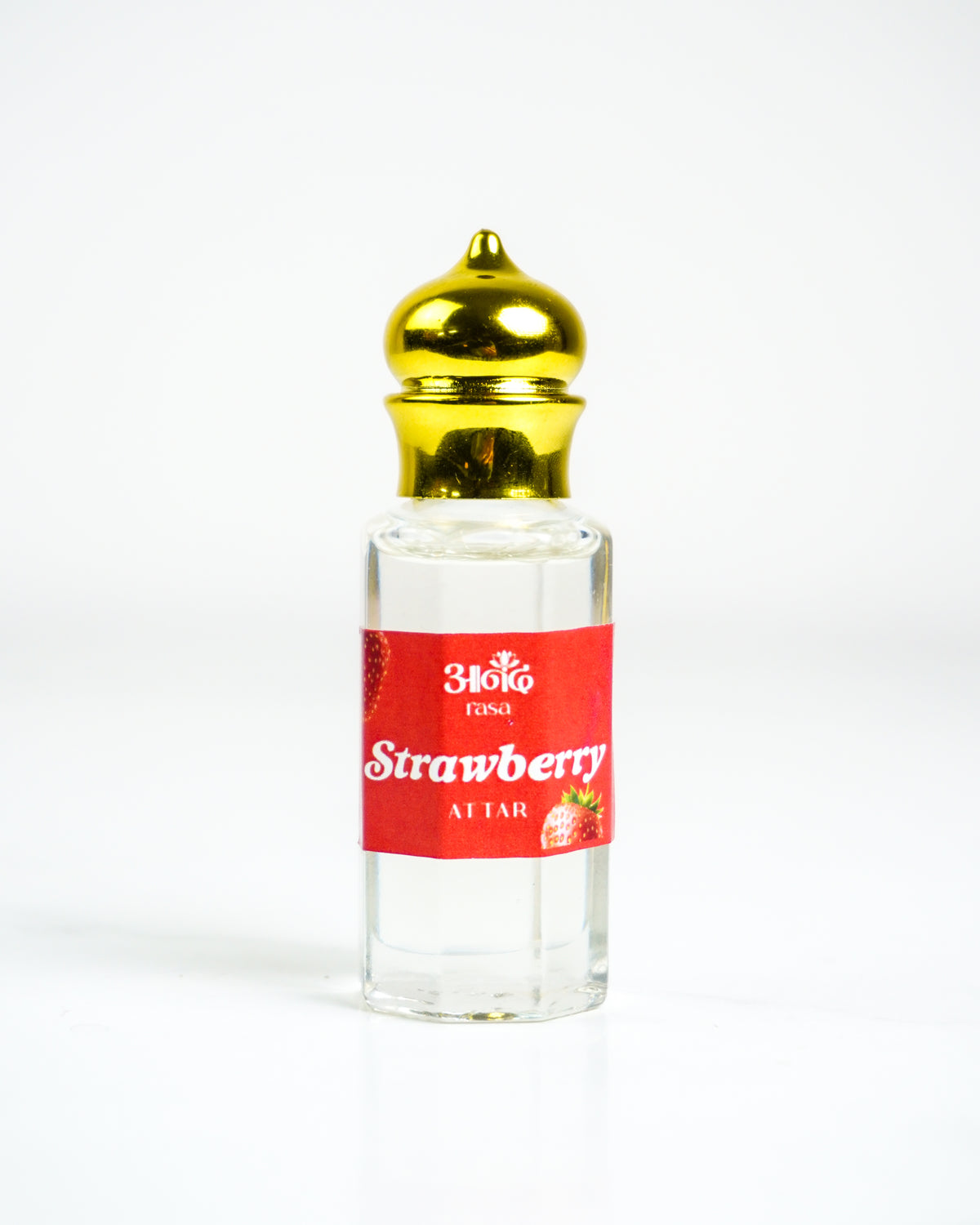 Rasa Strawberry Attar bottle surrounded by ripe strawberries on a white plate