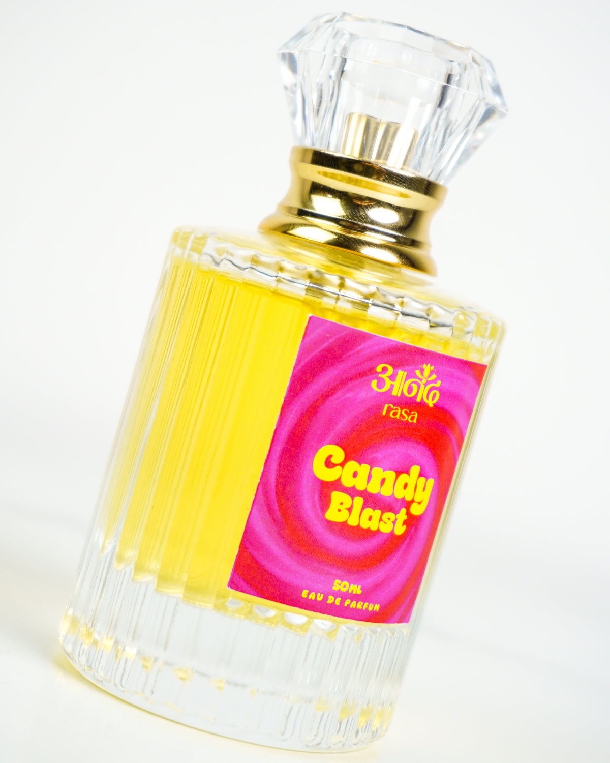 Candy Blast fragrance bottle photographed on a clean white background, featuring a colorful pink label and golden perfume liquid.